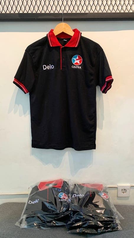 Polo hitam dengan kerah dan lengan merah serta bordir logo