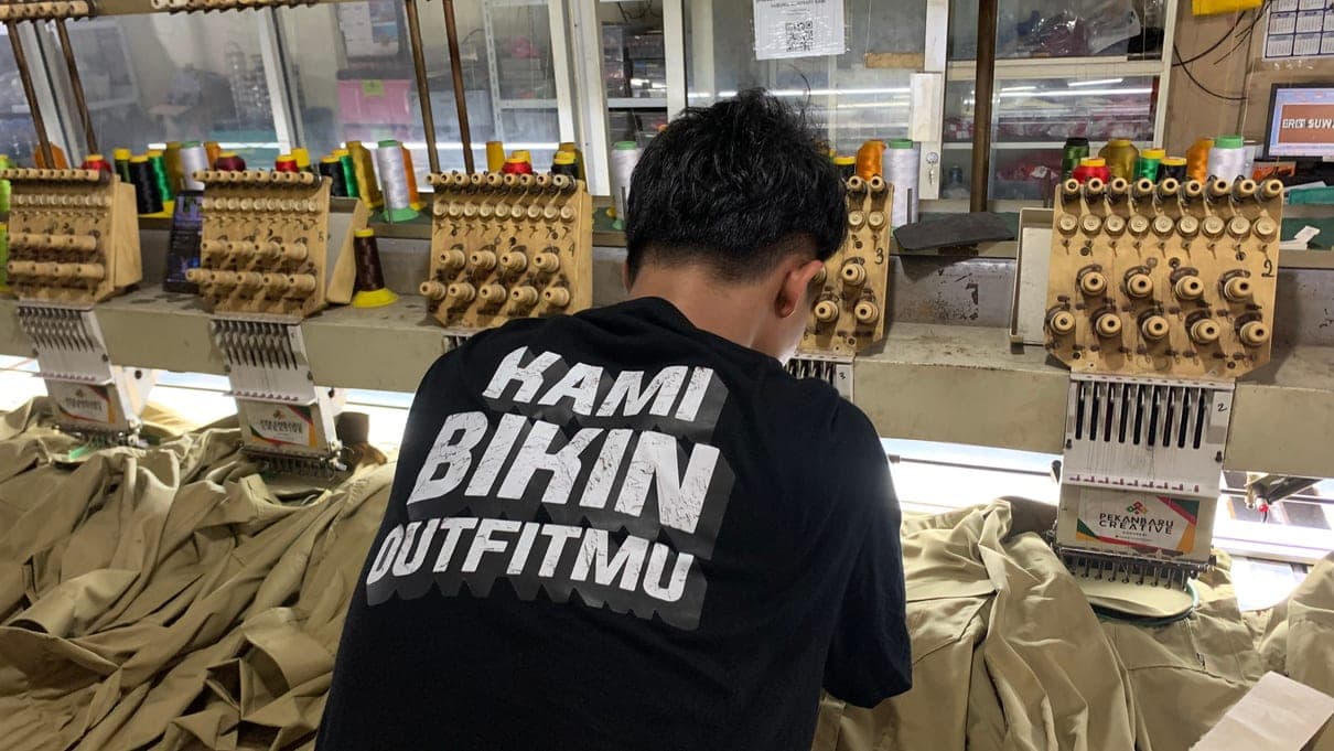 Operator berkaos “Kami Bikin Outfitmu” mengawasi mesin bordir