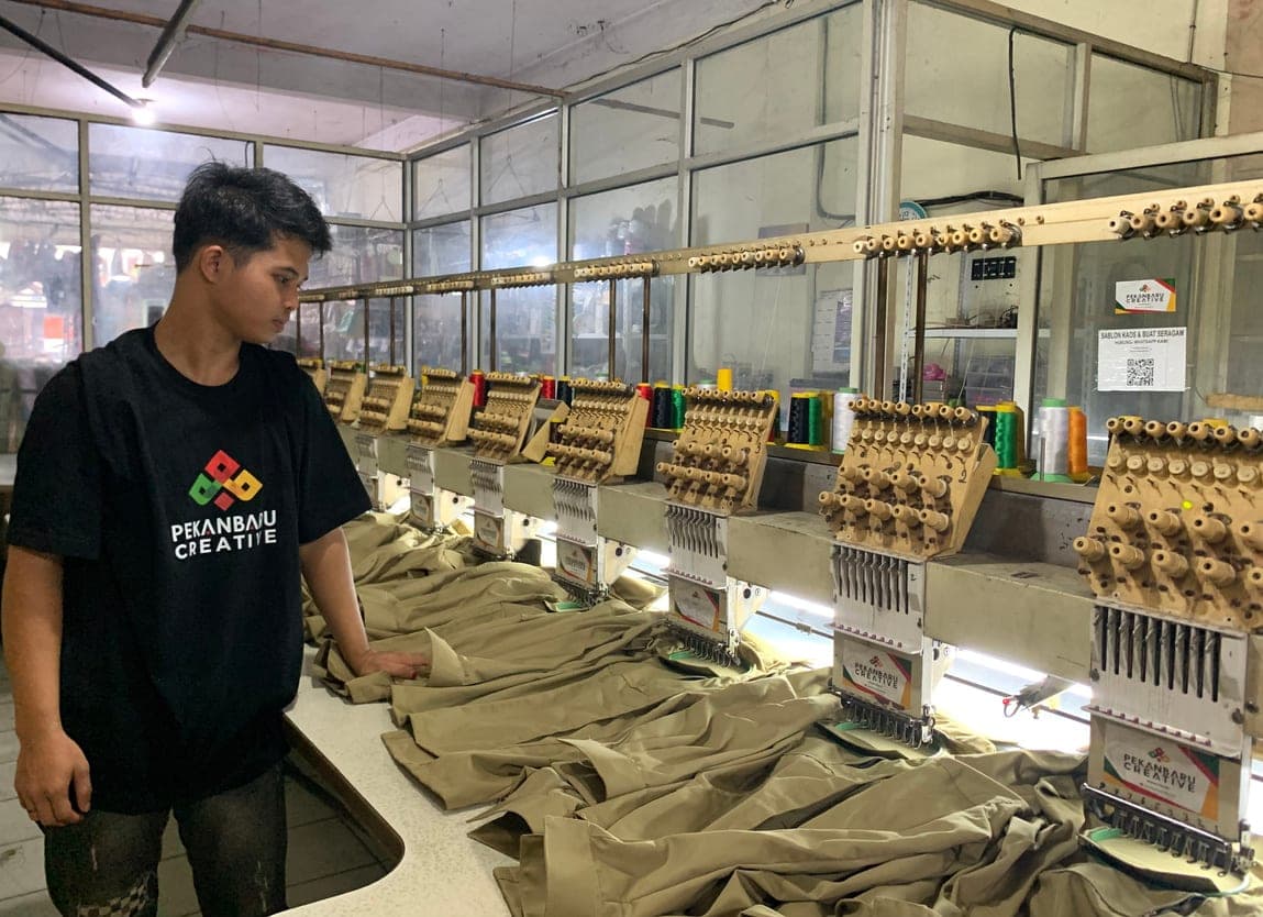 Deretan mesin bordir komputer multi-kepala sedang membordir kemeja seragam
